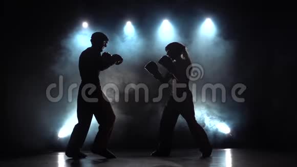 女人在用拳击踢人烟雾背景剪影慢动作视频的预览图