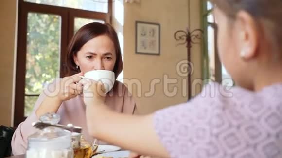快乐的女人在咖啡馆里和她10岁的女儿喝茶视频的预览图
