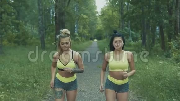 健身妇女在公园里跑步两名年轻女性慢动作在户外慢跑视频的预览图