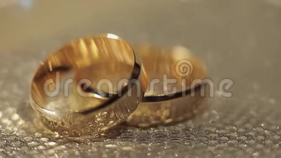 婚礼戒指躺在闪亮的光泽表面光芒四射特写视频的预览图