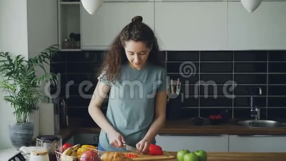 在家的厨房里一位身材魁梧的女人在餐桌旁跳舞在切红椒的时候她的丈夫端着杯子来看她视频的预览图