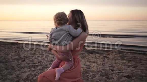 日落时分妈妈和女儿笑着沿着海滨散步视频的预览图
