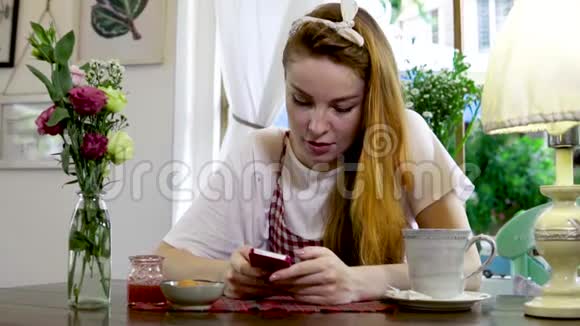 情绪化的女人一边喝茶一边在手机上聊天视频的预览图