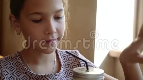 美丽的年轻女孩坐在咖啡馆里用吸管喝鸡尾酒视频的预览图