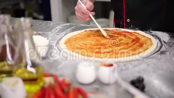 餐厅厨房厨师把番茄酱放在面团上视频的预览图