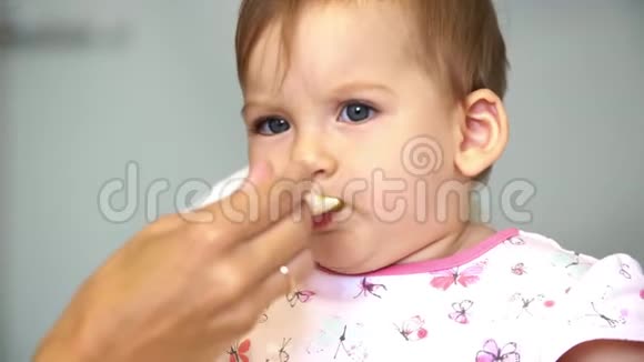 女儿从妈妈那里拿勺子妈妈用一勺蔬菜喂小孩吃午饭视频的预览图