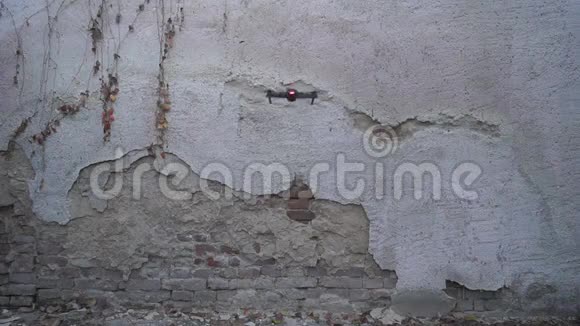 可折叠无人机在旧墙前盘旋的后视图视频的预览图