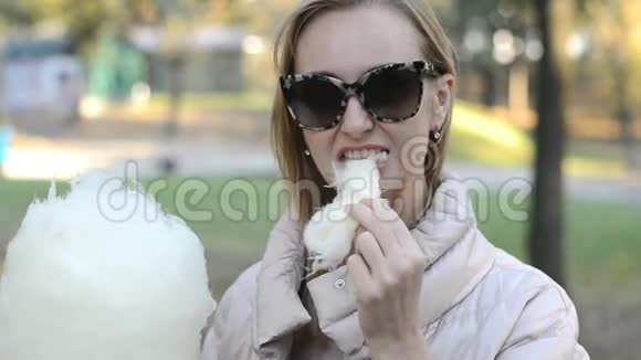 金发女孩在公园里吃棉花糖视频的预览图