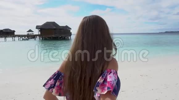 马尔代夫海滩上的女人跑到海边邀请她的朋友加入视频的预览图
