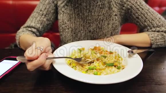 漂亮的白人女孩在咖啡馆里用手机吃泰国米饭和蔬菜视频的预览图