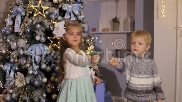 两个孩子在一棵圣诞树旁边放着火花视频的预览图