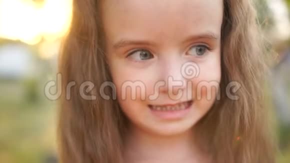 一个小而活泼的长发女孩的亲密肖像孩子笑露出乳牙夏日日落视频的预览图