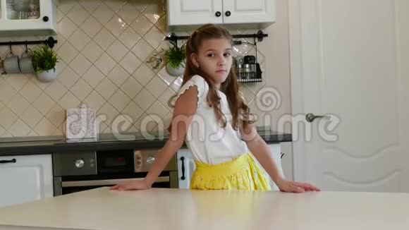可爱的金发女孩坐在厨房餐桌前视频的预览图