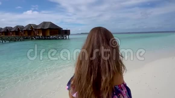 快乐的女人在马尔代夫的海边散步微笑和旋转视频的预览图