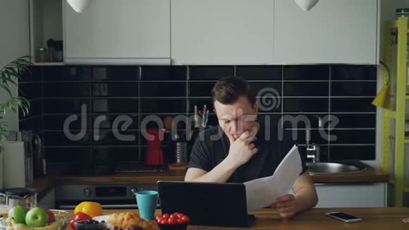 悲伤的不愉快的年轻人担心在家里用笔记本电脑支付账单他的女朋友来了视频的预览图