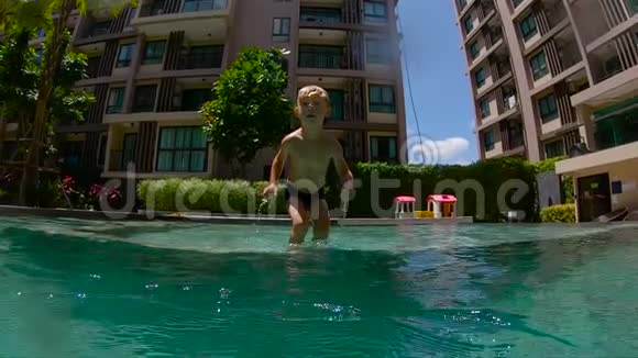一个可爱的小男孩手里拿着两颗在水下的鹅卵石潜入游泳池慢镜头视频的预览图
