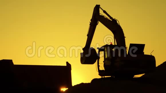 日落时将沙子装入卡车的挖掘机剪影概念建设和重工业机器意志视频的预览图