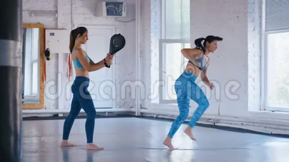 运动女性训练她的踢腿在她的持有的一个冲孔袋跆拳道或跆拳道的训练二视频的预览图