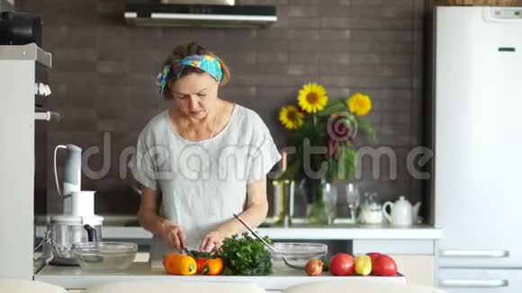 老妇人在家厨房做饭家庭主妇切黄瓜现代明亮的厨房内部素食主义视频的预览图