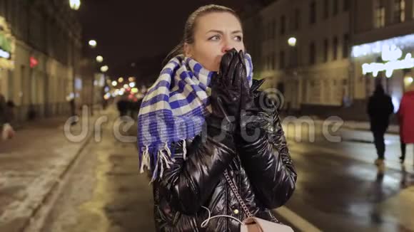 年轻女子在城市街头等待时感到寒冷和打喷嚏视频的预览图
