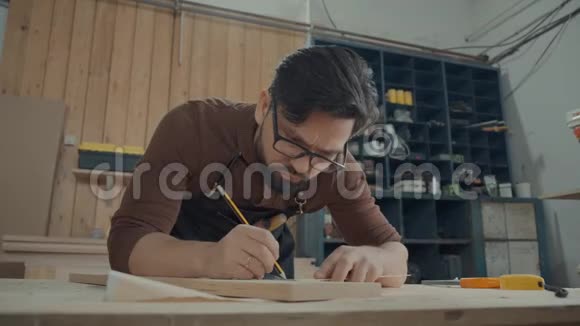 木工车间的人用铅笔在木条上做笔记视频的预览图