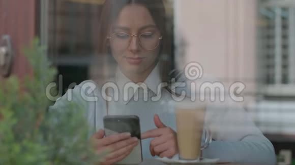 漂亮的女人在咖啡馆的智能手机上使用应用程序视频的预览图