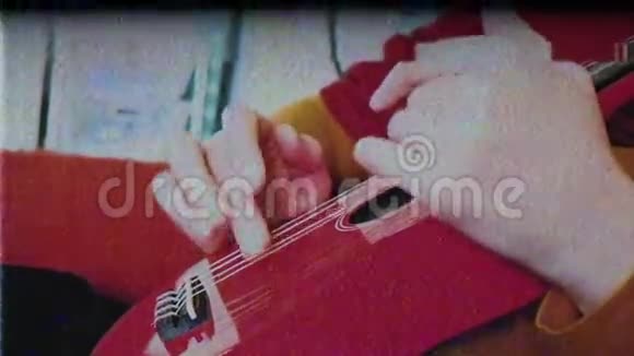 身穿红色连衣裙的女性手弹奏红色小曼陀林吉他视频的预览图