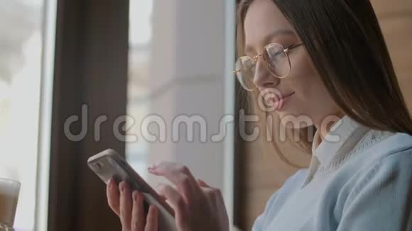 漂亮的女人在咖啡馆的智能手机上使用应用程序视频的预览图