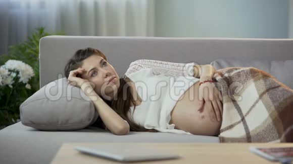 未来的妈妈躺在沙发上轻轻地揉着肚子想着未来期待着视频的预览图