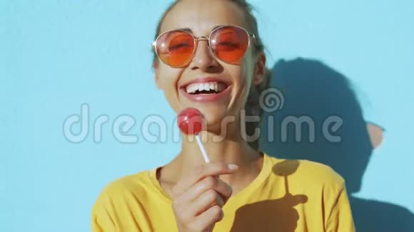 一个年轻的晒黑笑女人的脸特写带着红色眼镜的开朗微笑的女人站在蓝边视频的预览图