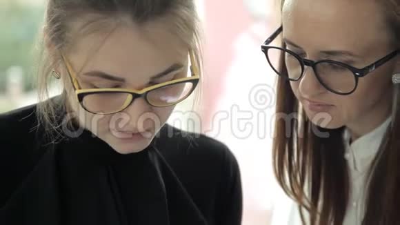 两个戴眼镜的年轻女商人在工作中讨论商业发展视频的预览图