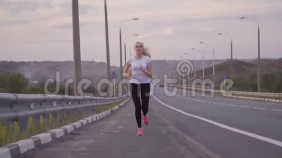 积极的生活方式体育女孩在城外的一条空跑道上跑步美丽的森林景观和日落视频的预览图