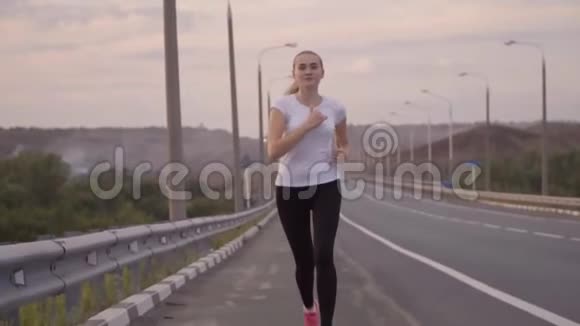 积极的生活方式体育女孩在城外的一条空跑道上跑步美丽的森林景观和日落视频的预览图