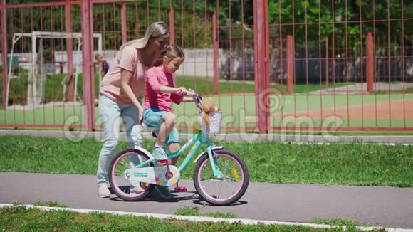 女人和女儿一起玩教她骑自行车视频的预览图