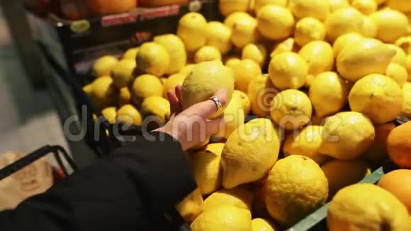 年轻的女人在超市里挑选新鲜的柠檬从有机农场挑选一位迷人的年轻人的双手特写视频的预览图