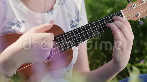 年轻漂亮的女孩弹着四弦琴吉他视频的预览图
