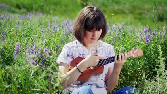 年轻漂亮的女孩弹着四弦琴吉他视频的预览图