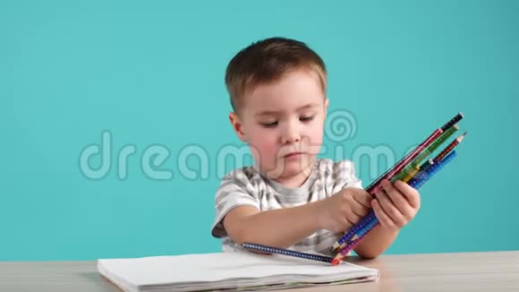 可爱的欧洲男孩用彩色铅笔在相册里坐在桌子旁视频的预览图