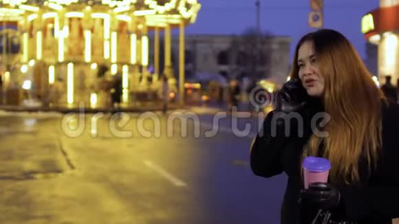 年轻情绪化的女人在旋转木马的背景下通过电话交谈视频的预览图