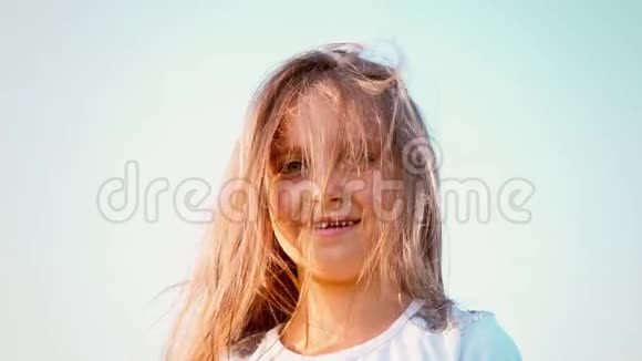 一个漂亮的小女孩长着飘逸的长发她的头朝不同的方向扭动女孩在玩她的头发视频的预览图