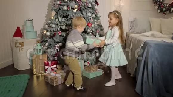 两个小朋友在圣诞树附近打开礼物视频的预览图