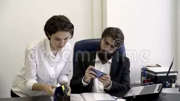 女秘书把重要的文件展示给她那长胡子的老板她在办公室里忙着玩智能手机游戏视频的预览图