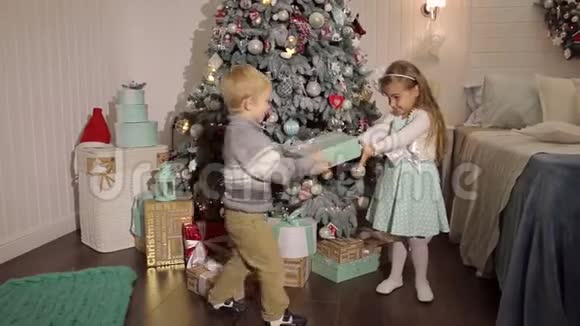 两个小朋友在圣诞树附近打开礼物视频的预览图