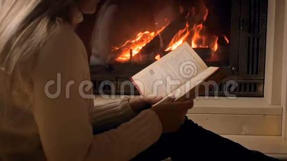 夜间坐在壁炉旁看书的慢动作录像视频的预览图