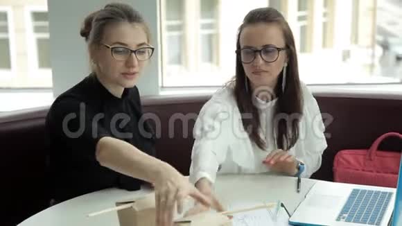 两个女孩坐在咖啡馆里吃面条讨论商业想法视频的预览图