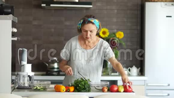一个现代的养老金领取者正在家里厨房准备沙拉她把西红柿浓缩她的头发被视频的预览图