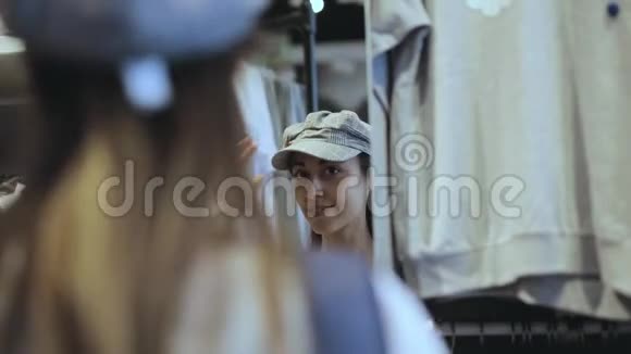 一个年轻女孩在镜子前的商店里试戴一顶帽子视频的预览图