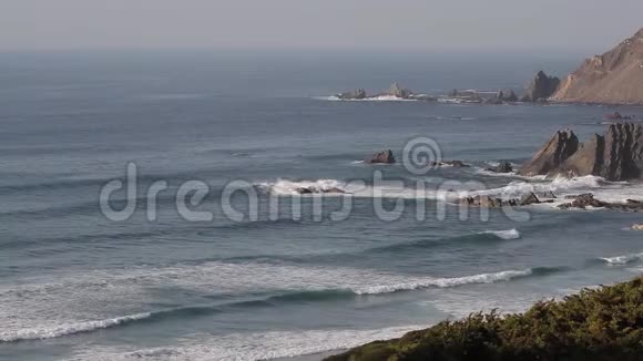 冲浪者在水中波浪靠近海滩背景是雾天和悬崖视频的预览图