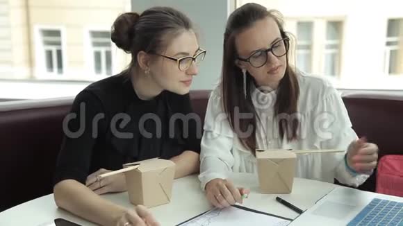 两个女孩坐在咖啡馆里吃面条讨论商业想法视频的预览图