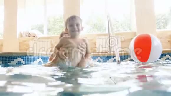4k视频快乐欢笑幼儿男孩与年轻母亲在室内游泳池游泳视频的预览图